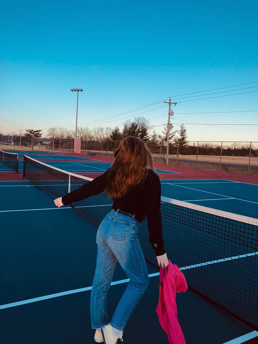 tennis court woman standing beside tennis net under clear blue sky person